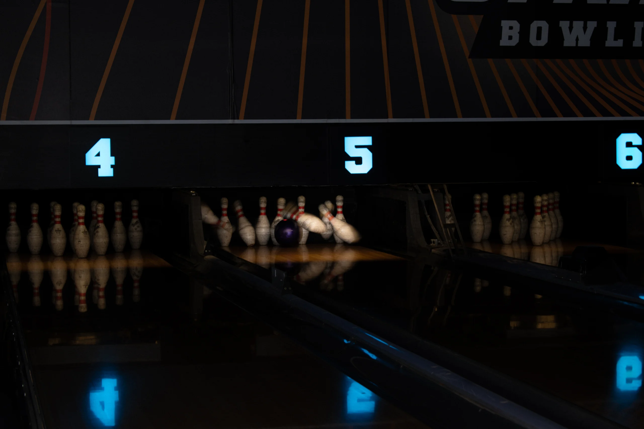Bowling ball striking the pins at the end of the lane